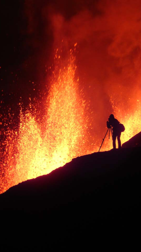 Person photographing a volcano at night